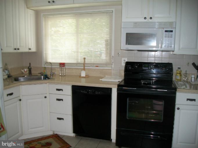 7310 Old Keene Mill Road Springfield, VA 22150 - Photo 9 of 30 a kitchen with granite countertop white cabinets and black appliances