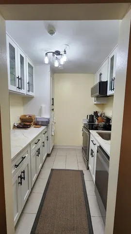 a kitchen with granite countertop white cabinets a sink dishwasher and a stove with wooden floor