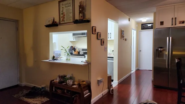 a view of a hallway with wooden floor and cabinets