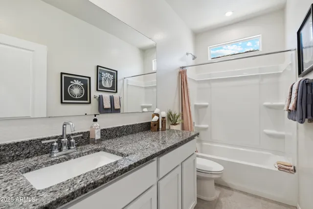 a bathroom with a granite countertop sink mirror vanity and toilet