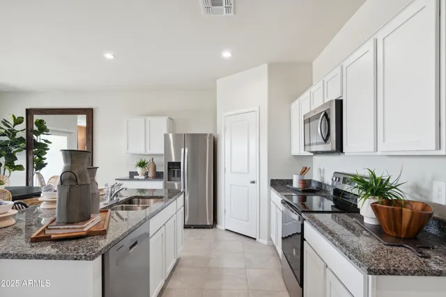 a kitchen with stainless steel appliances granite countertop a refrigerator a stove and a sink