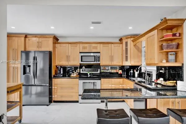 a kitchen with stainless steel appliances granite countertop a refrigerator and a stove