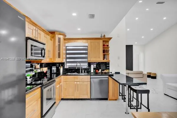 a kitchen with stainless steel appliances a sink a counter top space cabinets and a window