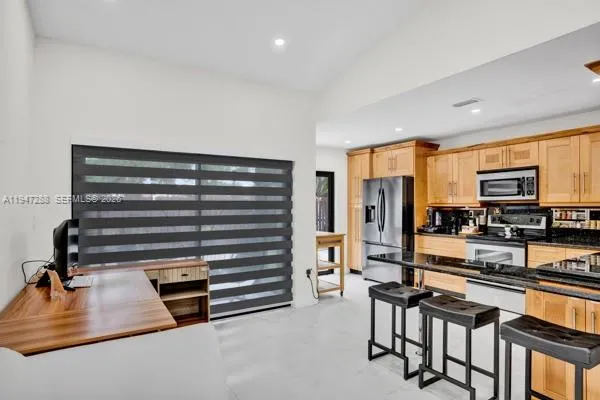 a kitchen with stainless steel appliances a stove top oven a refrigerator a dining table and chairs with wooden floor