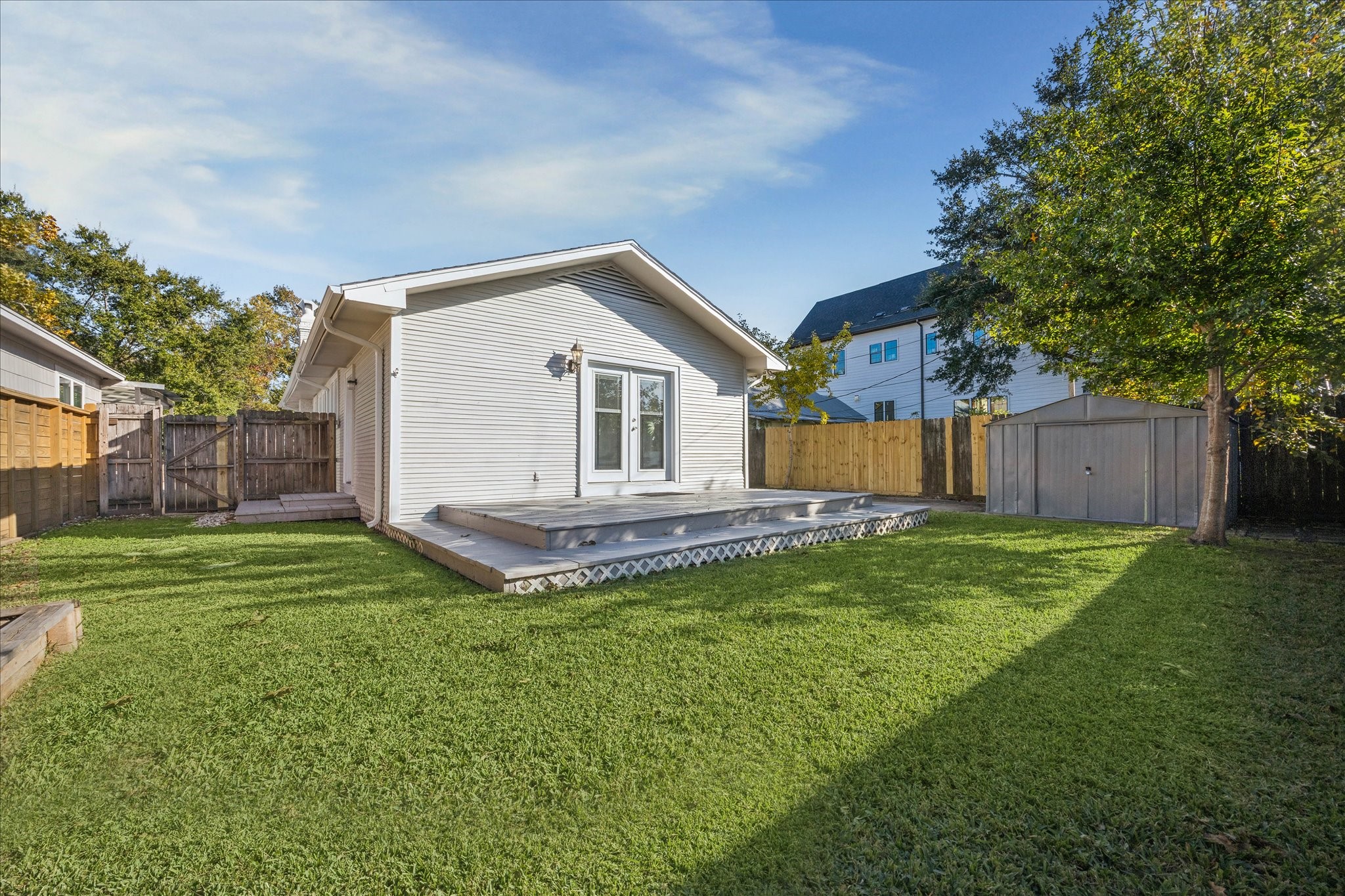 709 Walton Street Houston, TX 77009 - Photo 29 of 31 Fenced backyard with raised deck, storage shed, and open lawn area.