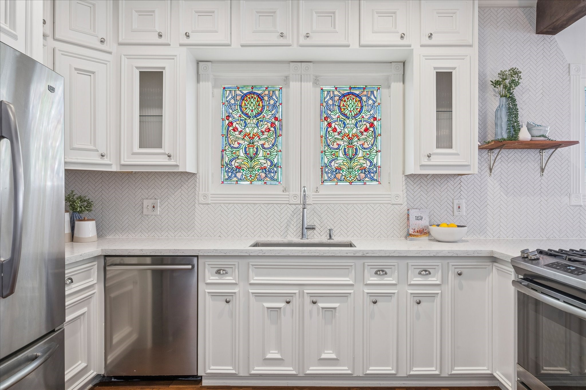 709 Walton Street Houston, TX 77009 - Photo 9 of 31 Clean kitchen layout featuring ample cabinet storage, modern finishes, and unique stained-glass accents.