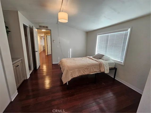 a bedroom with a bed window and wooden floor
