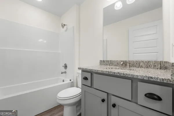 a bathroom with a granite countertop toilet sink and mirror