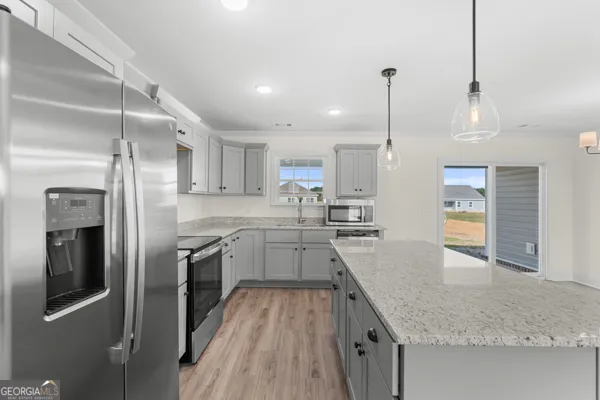 a large kitchen with granite countertop a large counter top appliances and cabinets