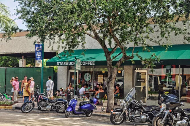 a front view of multi story residential apartment building with yard and outdoor seating