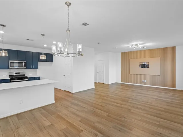 a view of a kitchen with kitchen island wooden floor and stainless steel appliances