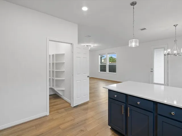 a room with a wooden floor and white cabinets