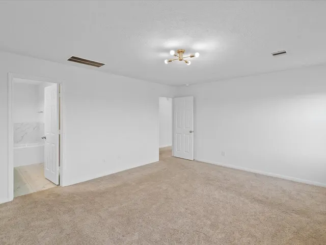 a view of an empty room with a chandelier fan