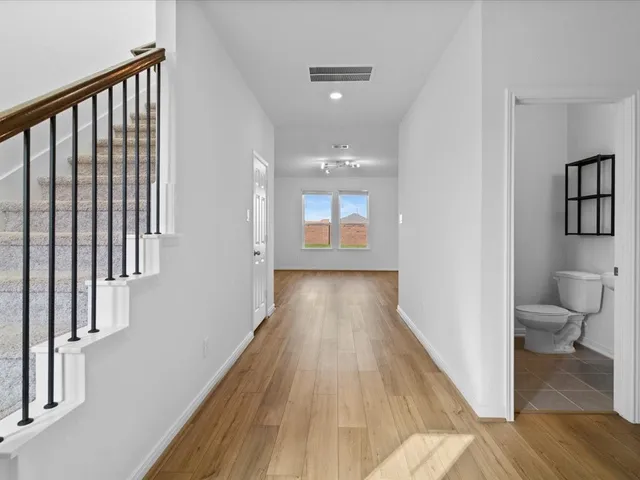 a view of a hallway with wooden floor and a bathroom