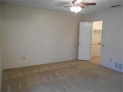 an empty room with a chandelier fan and windows