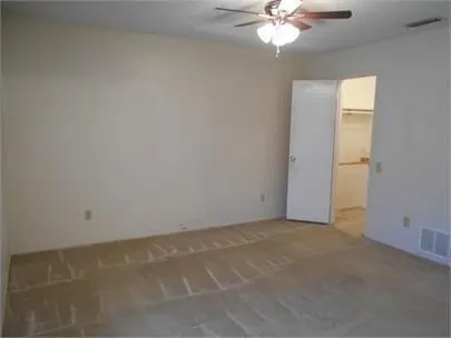 an empty room with a chandelier fan and windows