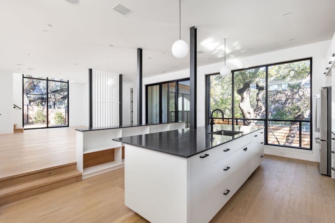 1603 Chelsea Lane, Unit 1 Austin, TX 78704 - Photo 11 of 40 Kitchen featuring white cabinetry, a spacious island, pendant lighting, light wood-style flooring, and modern cabinets