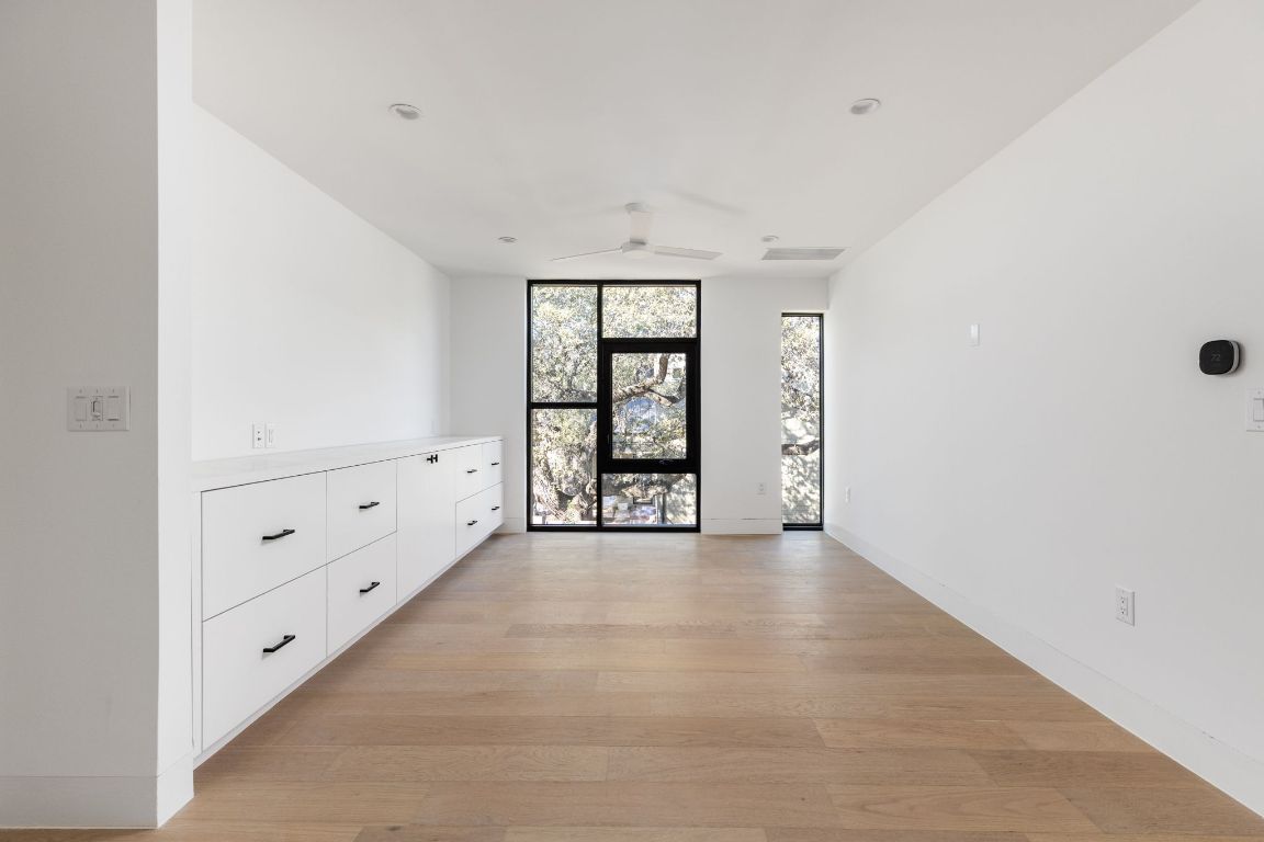 1603 Chelsea Lane, Unit 1 Austin, TX 78704 - Photo 22 of 40 Empty room featuring expansive windows, light wood-style floors, and ceiling fan