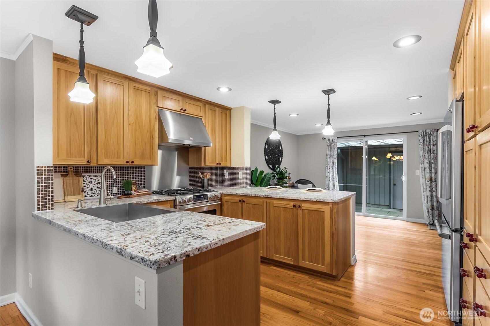 6524 Northeast 171st Place Kenmore, WA 98028 - Photo 13 of 35 a kitchen with kitchen island granite countertop wooden cabinets and a wooden floor