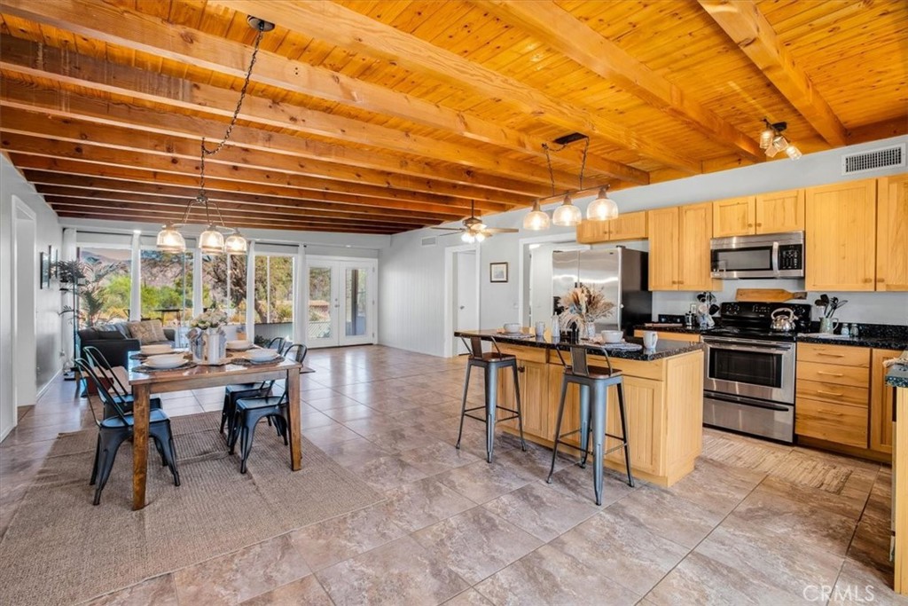 9384 Piedras Trail Morongo Valley, CA 92256 - Photo 18 of 75 a kitchen with stainless steel appliances kitchen island granite countertop a table chairs sink and cabinets