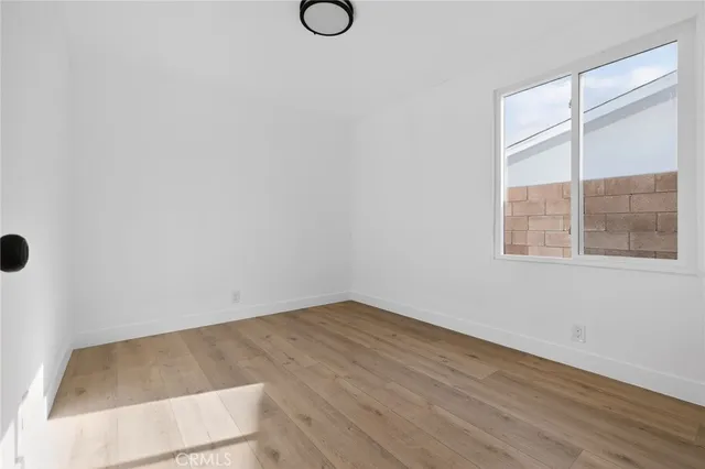 a view of an empty room with wooden floor and windows