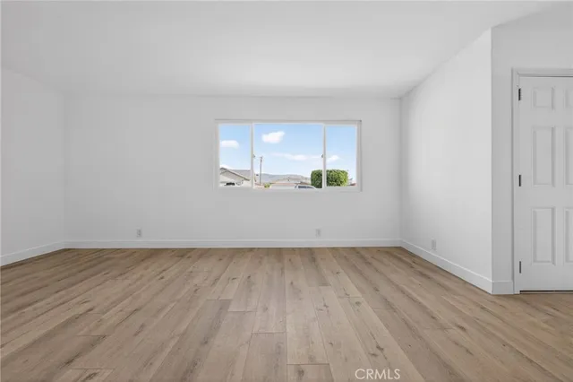 an empty room with wooden floor and window