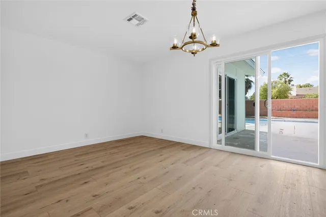 en empty room with wooden floor and chandelier