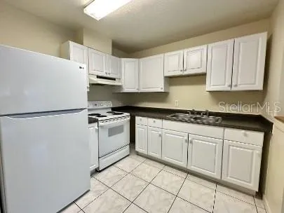 a kitchen with granite countertop white cabinets and white appliances