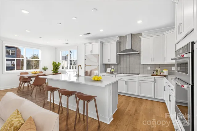 a kitchen with stainless steel appliances granite countertop a stove a sink a dining table and chairs