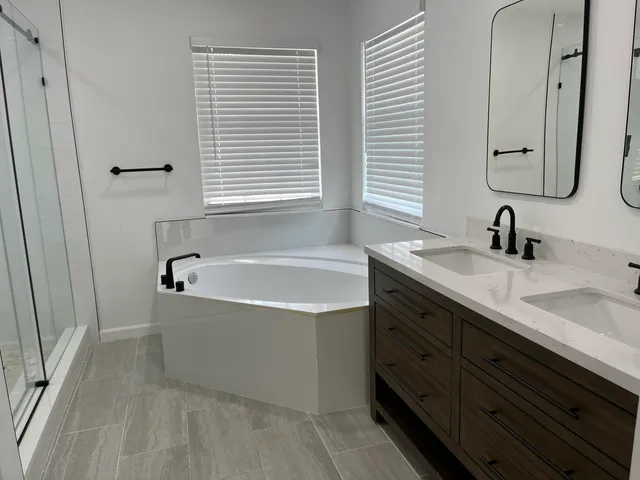 a bathroom with a tub double vanity sink and mirror