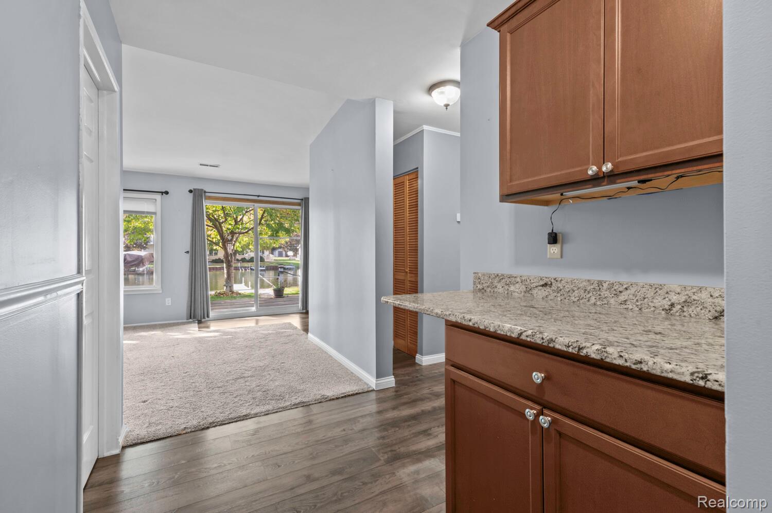 11026 Colony Pinckney, MI 48169 - Photo 21 of 40 Kitchen featuring light stone counters, dark wood-style flooring, ornamental molding, and dark colored carpet