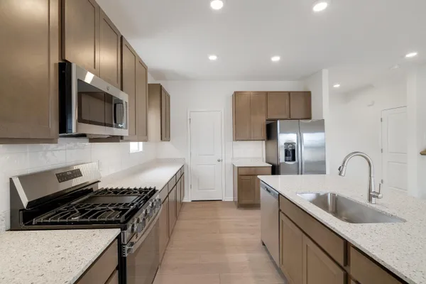 a kitchen with stainless steel appliances a sink a stove and a refrigerator with wooden floor