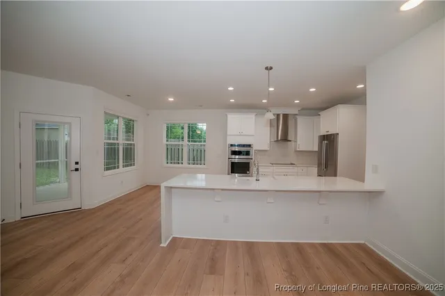 a large kitchen with stainless steel appliances a large counter top a stove and a refrigerator