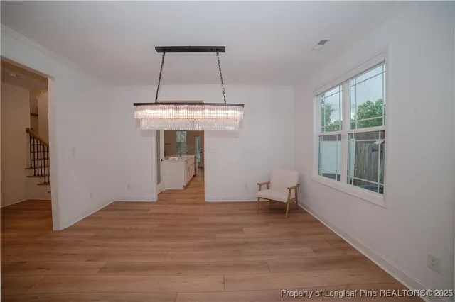 a view of a room with wooden floor chandeliers and kitchen