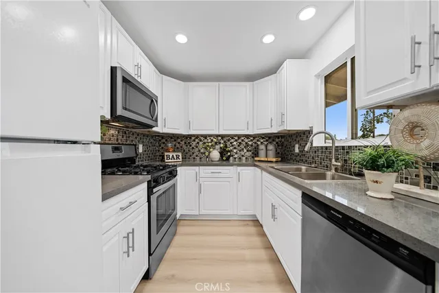 a kitchen with stainless steel appliances granite countertop lots of white cabinets a sink and dishwasher