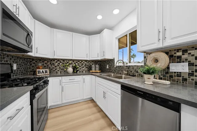 a kitchen with granite countertop white cabinets stainless steel appliances and a counter space