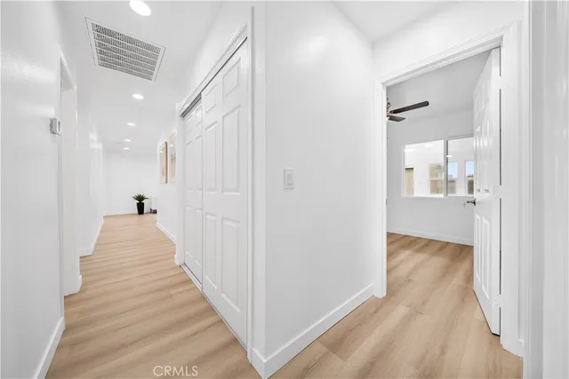 a view of a hallway with wooden floor and a bathroom