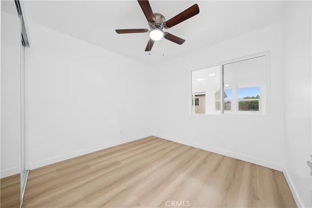 an empty room with wooden floor and ceiling fan