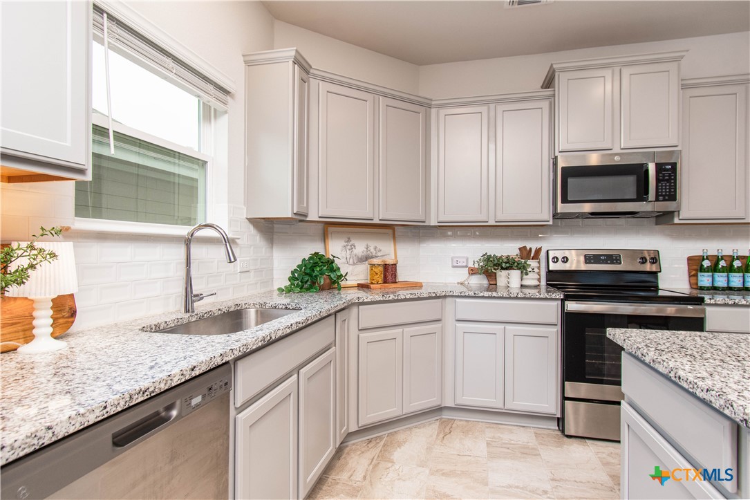 736 Jersey Court Troy, TX 76579 - Photo 6 of 32 a kitchen with granite countertop a sink stainless steel appliances and white cabinets