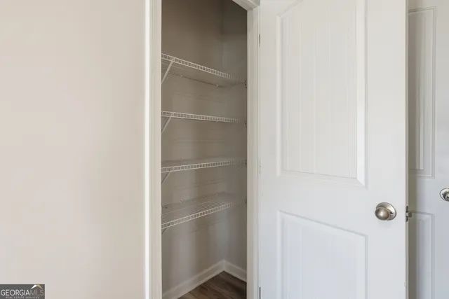 a walk in closet with wooden floor