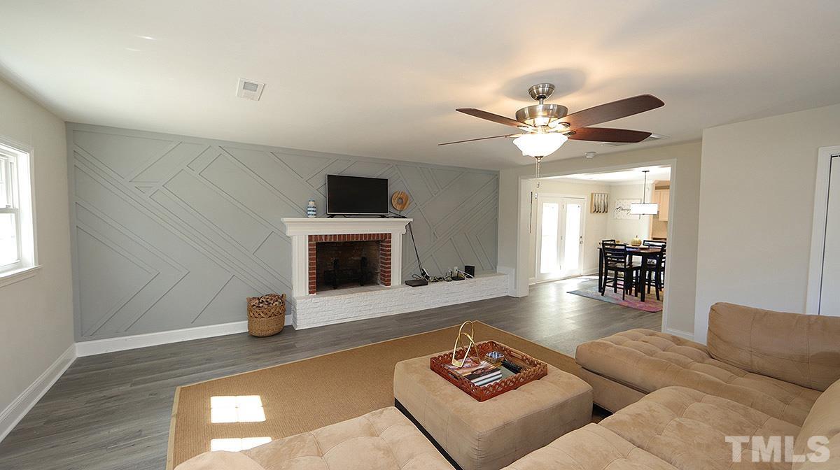 3811 Pickett Road Durham, NC 27705 - Photo 11 of 22 a living room with furniture a fireplace and a flat screen tv