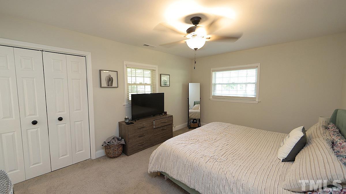 3811 Pickett Road Durham, NC 27705 - Photo 12 of 22 a bedroom with a bed and a flat tv screen on the dresser
