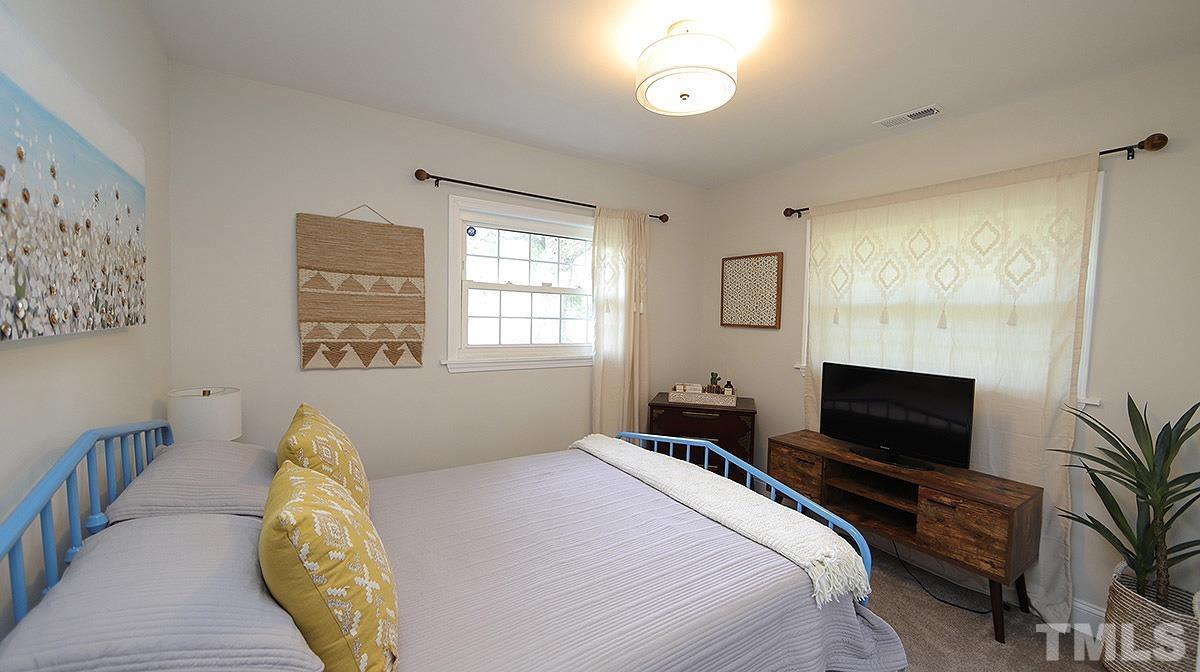 3811 Pickett Road Durham, NC 27705 - Photo 15 of 22 a bedroom with a bed and flat screen tv