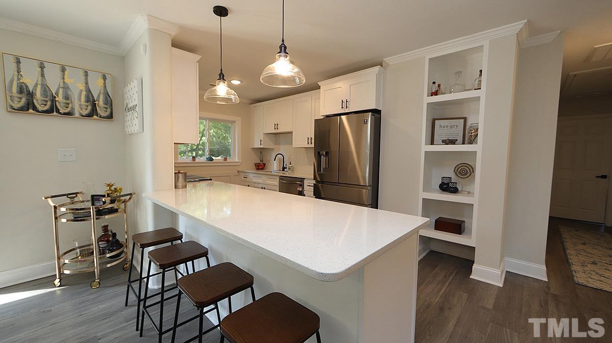 3811 Pickett Road Durham, NC 27705 - Photo 5 of 22 a kitchen with a refrigerator a stove and a dining table with wooden floor