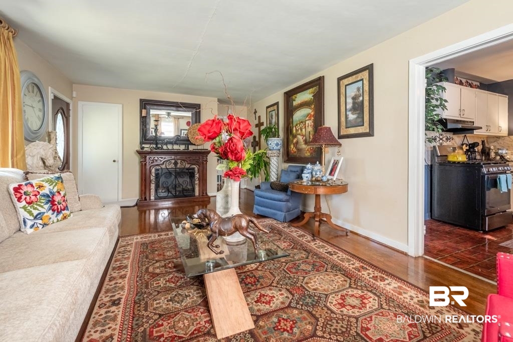 109 Esplanade Avenue Mobile, AL 36606 - Photo 6 of 45 Living room with dark wood-type flooring and a fireplace with raised hearth