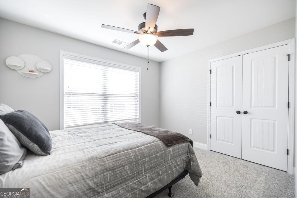 132 Sadie Heights Boulevard Perry, GA 31069 - Photo 19 of 29 a bedroom with a large bed and a ceiling fan