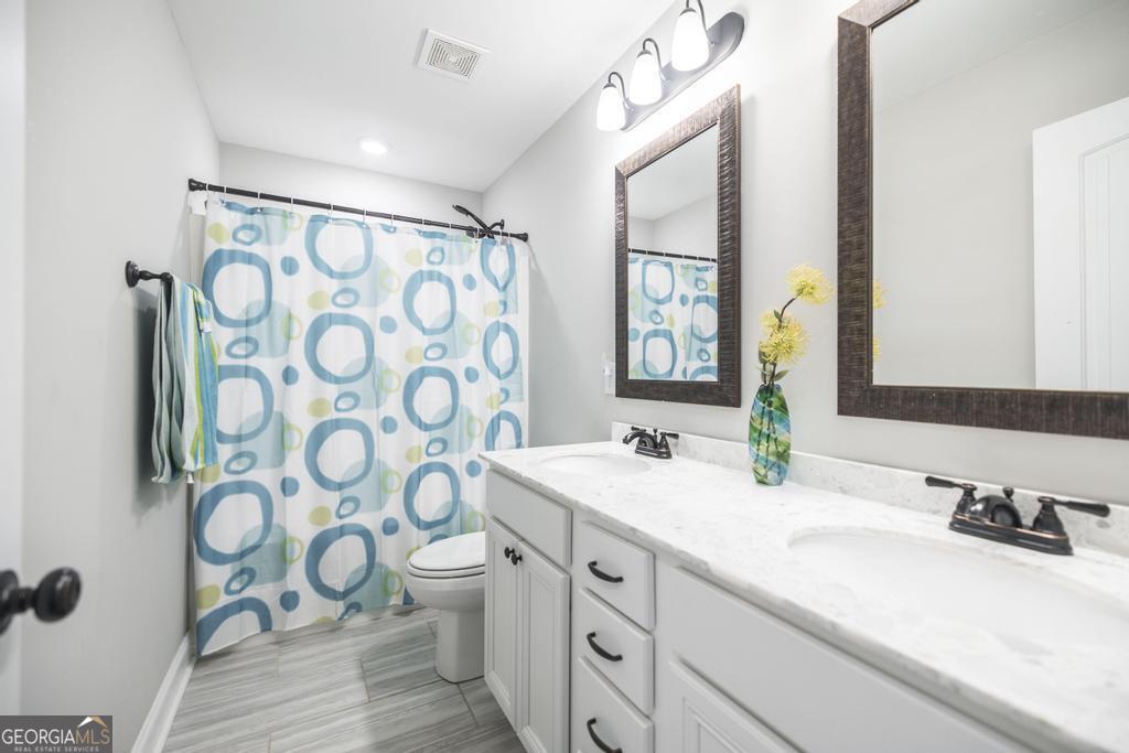 132 Sadie Heights Boulevard Perry, GA 31069 - Photo 24 of 29 a bathroom with a granite countertop sink a toilet and a mirror