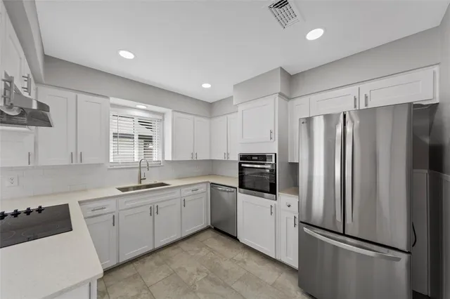 a kitchen that has a refrigerator a sink and white cabinets
