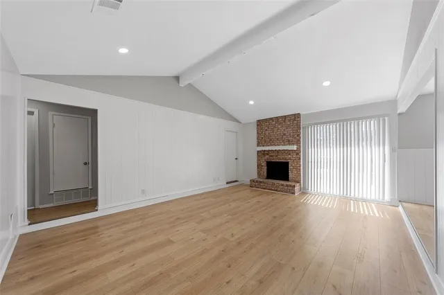an empty room with wooden floor and fireplace