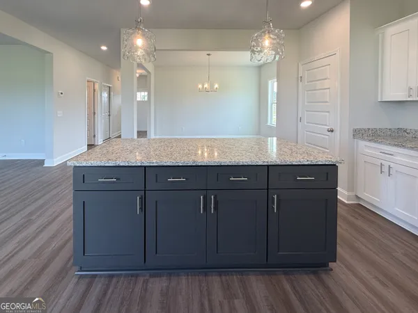 a view of granite countertop kitchen island wooden floors and stainless steel appliances